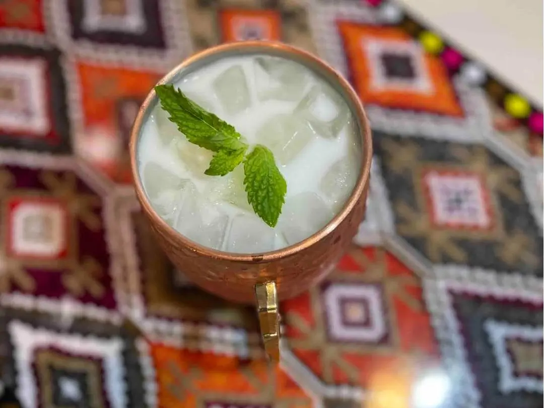 A milk - based drink garnished with mint leaves at Babahan Uyghur Cafe, a Chinese Xinjiang Flavors Restaurant in Plano