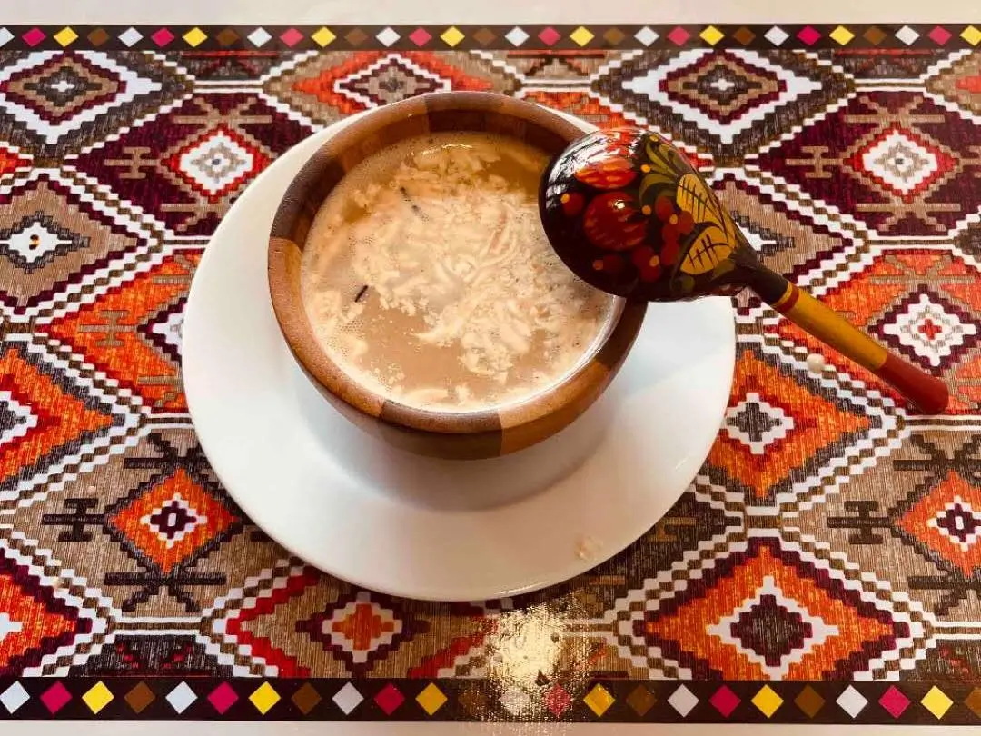 A traditional Xinjiang - style soup served in a wooden bowl at Babahan Uyghur Cafe, a Chinese Xinjiang Flavors Restaurant in Plano
