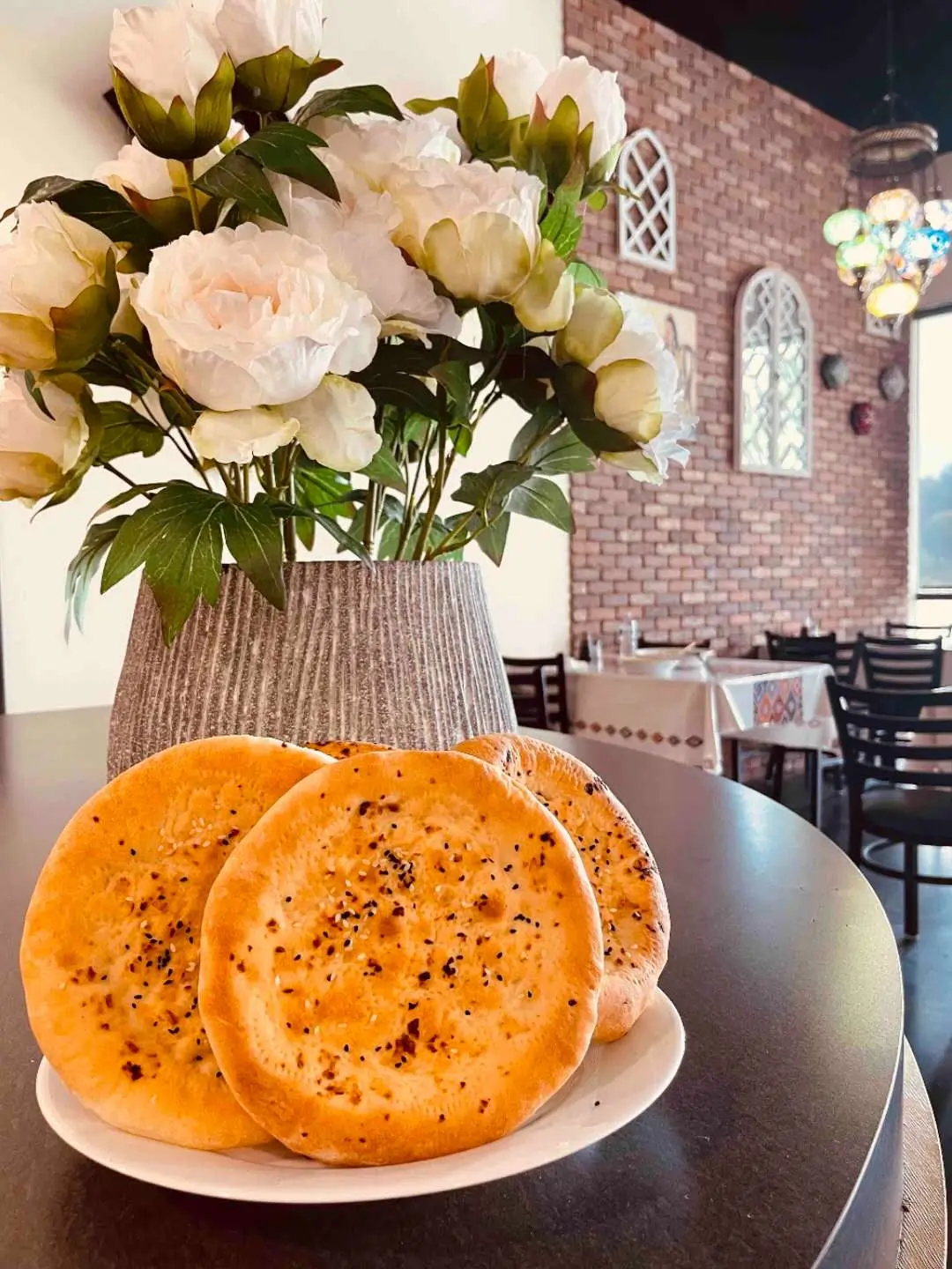 Babahan-Uyghur-Cafe-Chinese-Xinjiang-Flavors-Restaurant-Naan-Bread-with-Flowers-Plano Naan bread presented with a bouquet of flowers in the background at Babahan Uyghur Cafe, a Chinese Xinjiang Flavors Restaurant in Plano